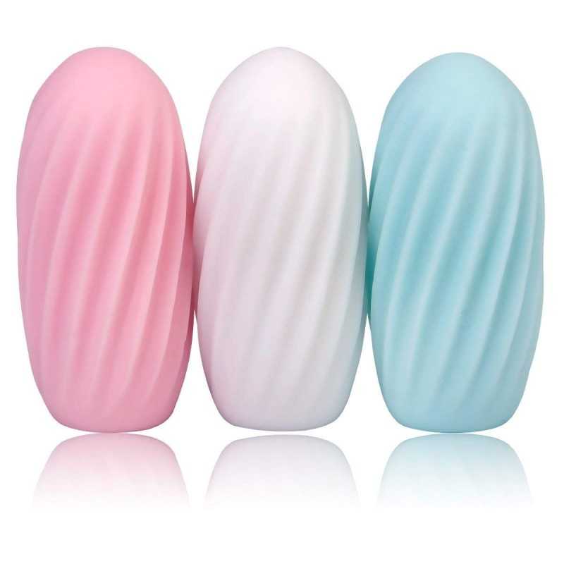 Overhead flat-lay photograph of three small ribbed oval-shaped items in soft pink, white, and teal standing upright on a clean white background, soft reflections, calm pastel mood.